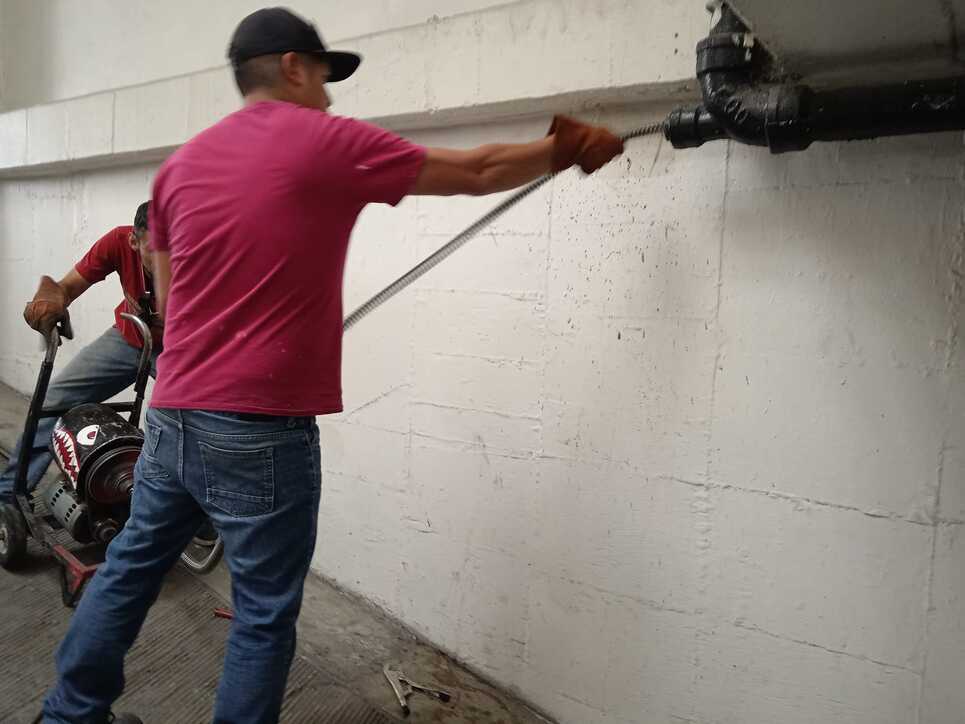 Dos trabajadores limpiado tuberia con una maquina especial para destaparcaños